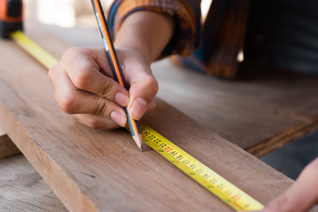 Craftsman measuring and marking wood at Phillips Lumber & Millwork
